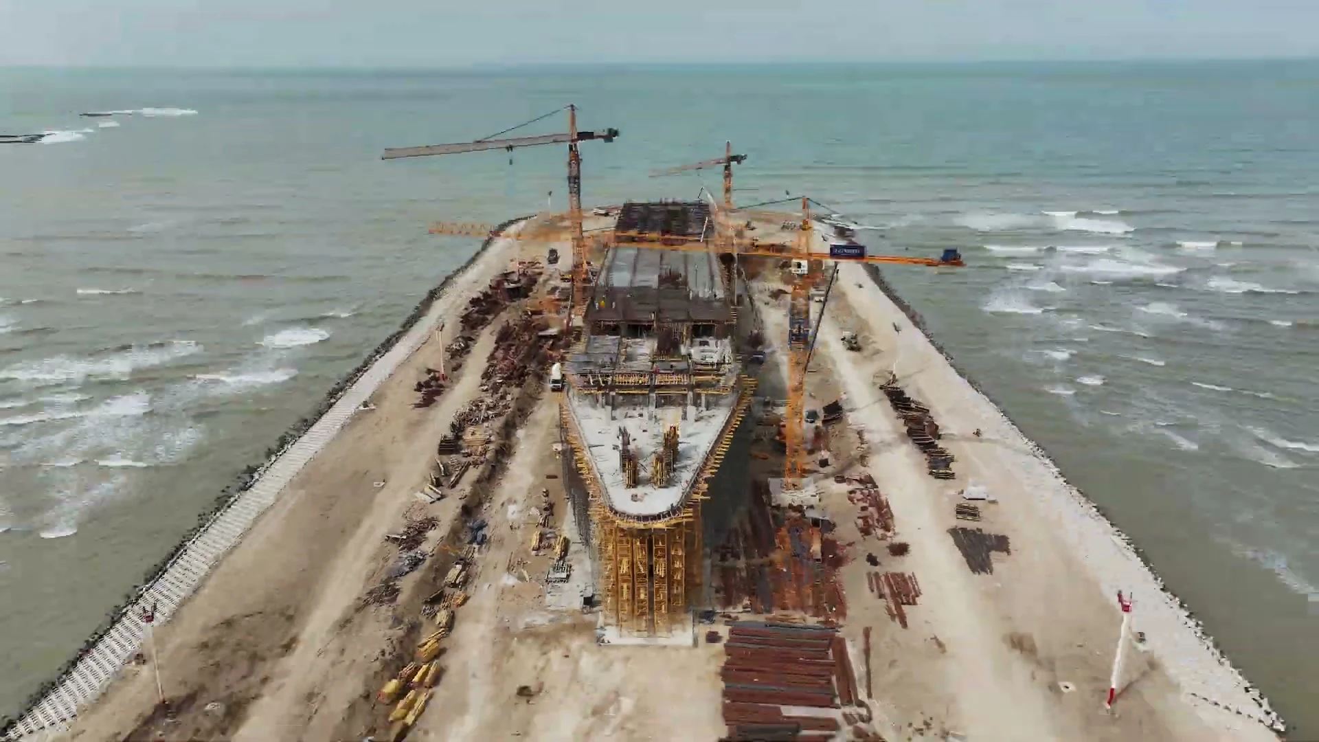 A ship-shaped building on a man-made spit, seen from the sea
